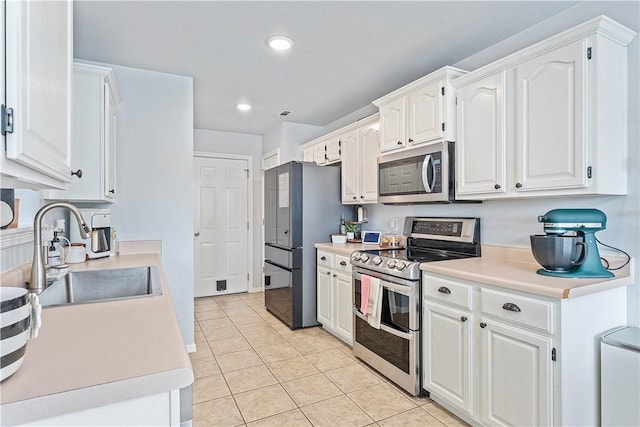 1031 Charles St, Pea Ridge, AR 72751 - kitchen featuring appliances with stainless steel finishes, a sink, light tile patterned floors, white cabinets, and light countertops