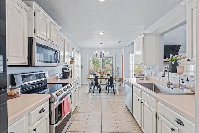 1031 Charles St, Pea Ridge, AR 72751 - kitchen with appliances with stainless steel finishes, a sink, a chandelier, light tile patterned floors, and light countertops