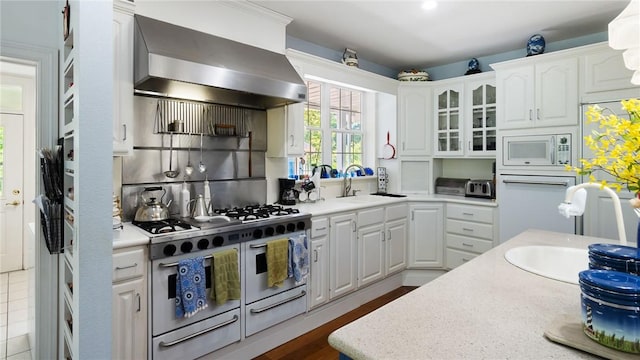 14559 Zimmerman Ln, Rogers, AR 72756 - kitchen with wall chimney exhaust hood, white appliances, white cabinetry, light countertops, and a sink
