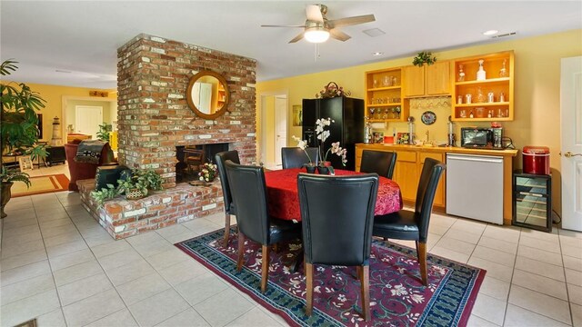 14559 Zimmerman Ln, Rogers, AR 72756 - dining space with wine cooler, light tile patterned floors, a ceiling fan, a brick fireplace, and bar