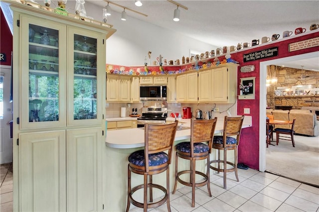 4 Branchwood Ln, Bella Vista, AR 72715 - kitchen with stainless steel appliances, light tile patterned floors, light countertops, light colored carpet, and cream cabinetry