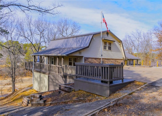 2480 N Saint Andrews Dr, Kansas, OK 74347 - view of front of house featuring a gambrel roof, brick siding, metal roof, and a deck