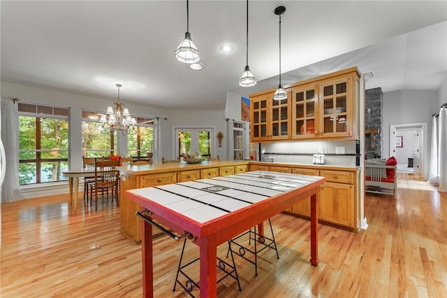 47 Rath Dr, Bella Vista, AR 72715 - kitchen with a peninsula, light wood-style flooring, glass insert cabinets, a chandelier, and light countertops