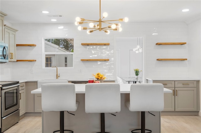 1089 Elway Dr, Springdale, AR 72764 - kitchen featuring open shelves, appliances with stainless steel finishes, gray cabinets, a kitchen island, and a breakfast bar area