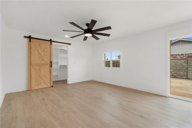 1089 Elway Dr, Springdale, AR 72764 - unfurnished bedroom featuring a barn door, light wood-style floors, baseboards, a walk in closet, and recessed lighting