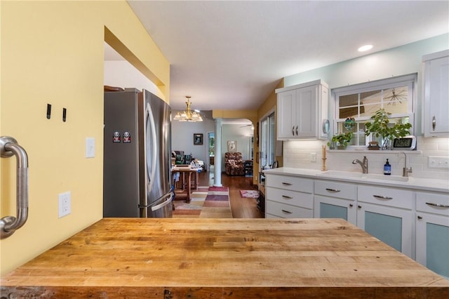 16 Osage Ln, Holiday Island, AR 72631 - kitchen featuring freestanding refrigerator, a sink, decorative backsplash, a chandelier, and wooden counters