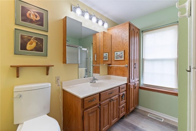 16 Osage Ln, Holiday Island, AR 72631 - bathroom featuring vanity, wood finished floors, toilet, baseboards, and a shower with shower door