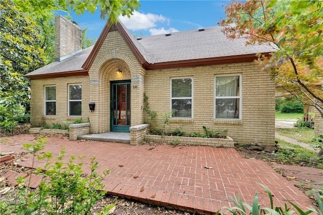 320 S Pleasant St, Springdale, AR 72764 - view of front facade featuring a chimney, brick siding, a patio area, and roof with shingles
