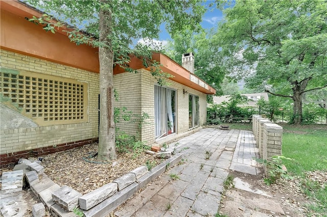 320 S Pleasant St, Springdale, AR 72764 - view of property exterior with brick siding, a patio area, and a chimney