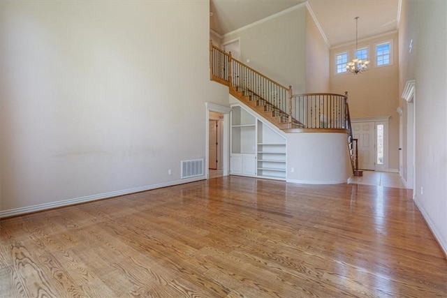 4204 Warbal Trl, Rogers, AR 72758 - unfurnished living room with stairs, a chandelier, a high ceiling, ornamental molding, and wood finished floors