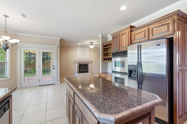 4204 Warbal Trl, Rogers, AR 72758 - kitchen with stainless steel appliances, brown cabinetry, a chandelier, a fireplace with raised hearth, and a ceiling fan