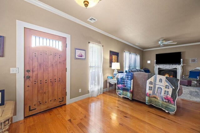 815 James Pl, West Fork, AR 72774 - foyer entrance with wood-type flooring, plenty of natural light, crown molding, a warm lit fireplace, and a ceiling fan