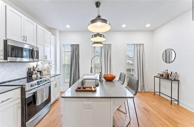 429 SW B St, Bentonville, AR 72712 - kitchen featuring appliances with stainless steel finishes, a sink, tasteful backsplash, white cabinetry, and light wood-type flooring