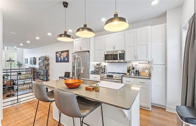 429 SW B St, Bentonville, AR 72712 - kitchen with appliances with stainless steel finishes, tasteful backsplash, recessed lighting, light wood finished floors, and white cabinetry