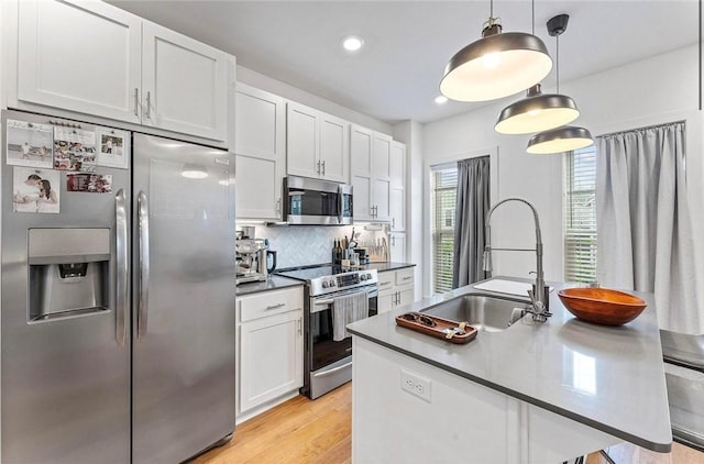 429 SW B St, Bentonville, AR 72712 - kitchen featuring appliances with stainless steel finishes, a sink, tasteful backsplash, pendant lighting, and a center island with sink