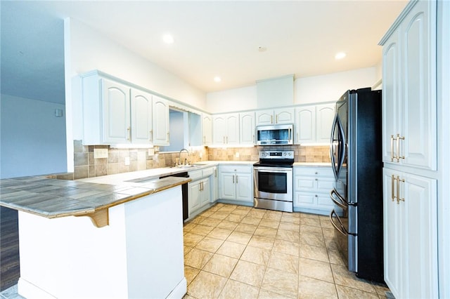 1813 SW Pine Ave, Bentonville, AR 72713 - kitchen with appliances with stainless steel finishes, a peninsula, backsplash, white cabinets, and tile countertops
