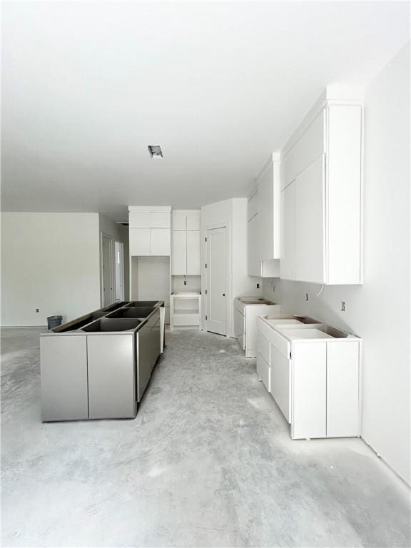 1 Breeghle Ln, Bella Vista, AR 72714 - kitchen with concrete flooring, washer / dryer, white cabinets, and modern cabinets