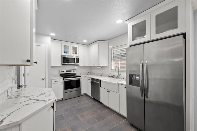 704 Del Cir, Lowell, AR 72745 - kitchen with appliances with stainless steel finishes, a sink, decorative backsplash, recessed lighting, and white cabinetry