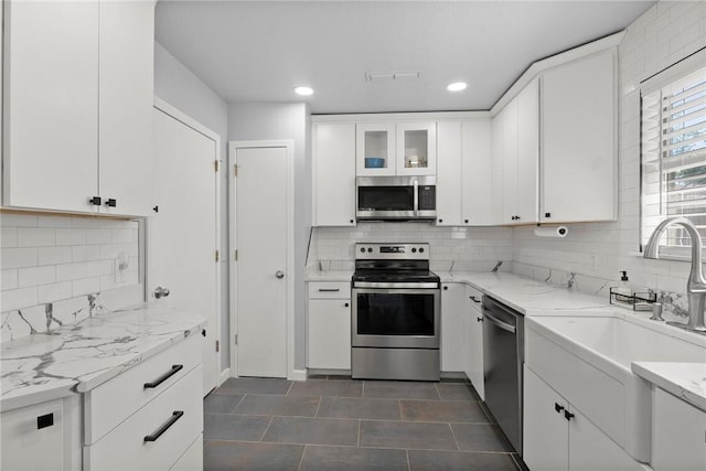 704 Del Cir, Lowell, AR 72745 - kitchen with appliances with stainless steel finishes, white cabinets, tasteful backsplash, recessed lighting, and light stone countertops