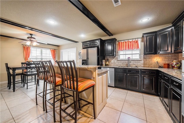 8266 Anna Maria Ave, Springdale, AR 72762 - kitchen featuring appliances with stainless steel finishes, a sink, dark cabinets, a breakfast bar area, and tasteful backsplash