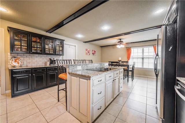 8266 Anna Maria Ave, Springdale, AR 72762 - kitchen featuring a kitchen bar, ceiling fan, a textured ceiling, dark cabinetry, and a kitchen island