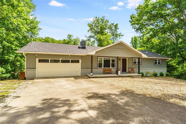21 Chudleigh Ln, Bella Vista, AR 72714 - ranch-style house with an attached garage, a chimney, concrete driveway, a porch, and a shingled roof