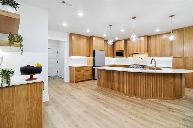 204 NE Healing Springs St, Bentonville, AR 72713 - kitchen featuring freestanding refrigerator, stainless steel microwave, decorative backsplash, light wood-style flooring, and recessed lighting
