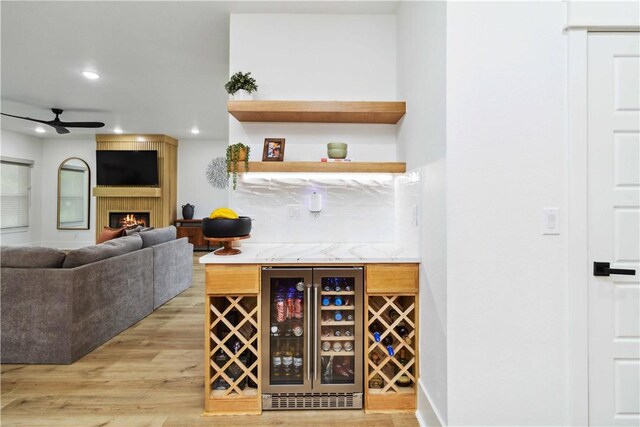204 NE Healing Springs St, Bentonville, AR 72713 - indoor dry bar featuring beverage cooler, a ceiling fan, recessed lighting, light wood-style flooring, and a large fireplace
