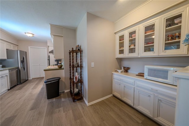 1608 Cartwright Cir, Springdale, AR 72762 - kitchen with appliances with stainless steel finishes, light wood finished floors, glass insert cabinets, light countertops, and baseboards