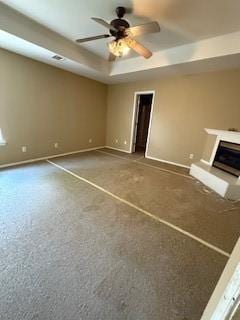 1210 Apache Dr, Bentonville, AR 72712 - unfurnished living room featuring baseboards, a tray ceiling, a fireplace with raised hearth, and ceiling fan