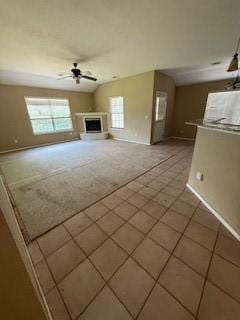 1210 Apache Dr, Bentonville, AR 72712 - unfurnished living room featuring healthy amount of natural light, tile patterned flooring, ceiling fan, and a fireplace with raised hearth