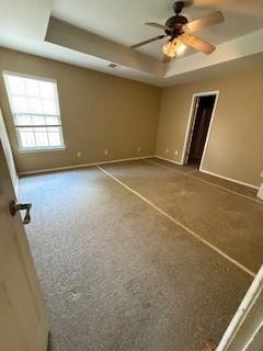1210 Apache Dr, Bentonville, AR 72712 - spare room with a raised ceiling, baseboards, ceiling fan, and carpet
