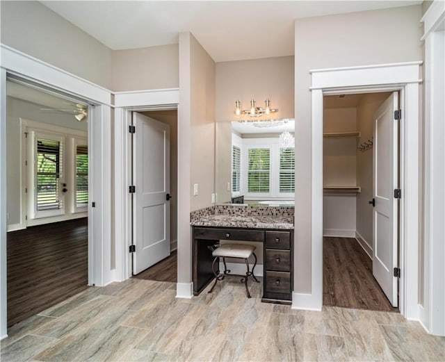 19643 Indigo Dr, Rogers, AR 72756 - bathroom with wood finished floors, vanity, baseboards, a walk in closet, and ceiling fan