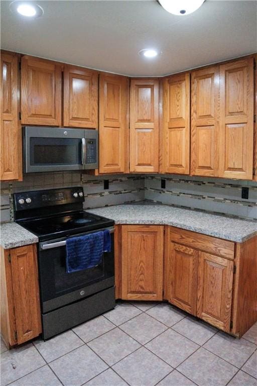 19105 Feather Hill Rd, Elkins, AR 72727 - kitchen featuring stainless steel microwave, black range with electric stovetop, brown cabinets, light countertops, and light tile patterned flooring