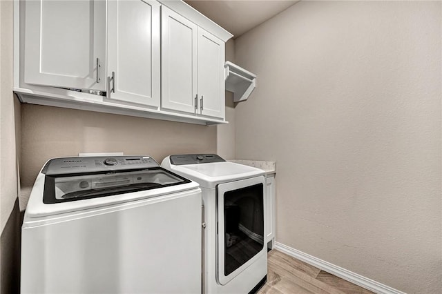 1300 Eureka Rd, Centerton, AR 72719 - laundry room featuring independent washer and dryer, cabinet space, baseboards, and light wood finished floors