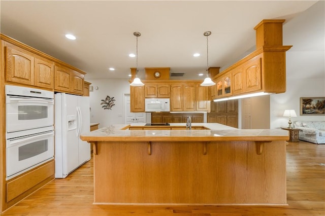 18 Cheviot Ln, Bella Vista, AR 72715 - kitchen featuring white appliances, light wood-style floors, a breakfast bar, a center island with sink, and recessed lighting
