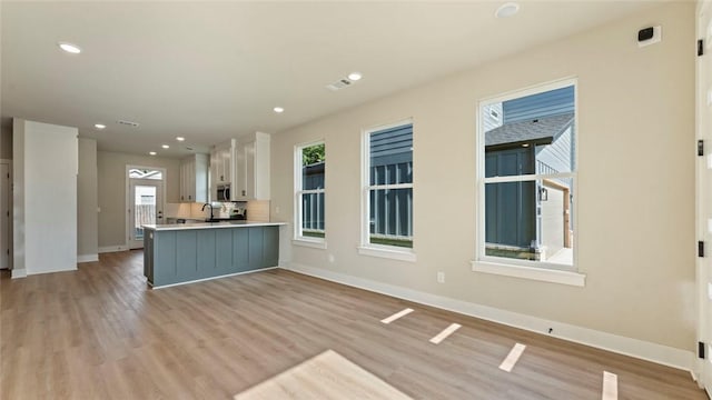 1209 SW Journey Ln, Bentonville, AR 72713 - kitchen featuring stainless steel microwave, light countertops, light wood finished floors, white cabinetry, and recessed lighting