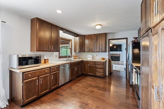 326 Hillcrest Rd, Eureka Springs, AR 72631 - kitchen featuring appliances with stainless steel finishes, a sink, dark wood-style flooring, a glass covered fireplace, and light countertops