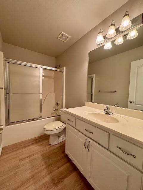 108 Hoss St, Centerton, AR 72719 - bathroom featuring toilet, vanity, wood finished floors, and shower / bath combination with glass door
