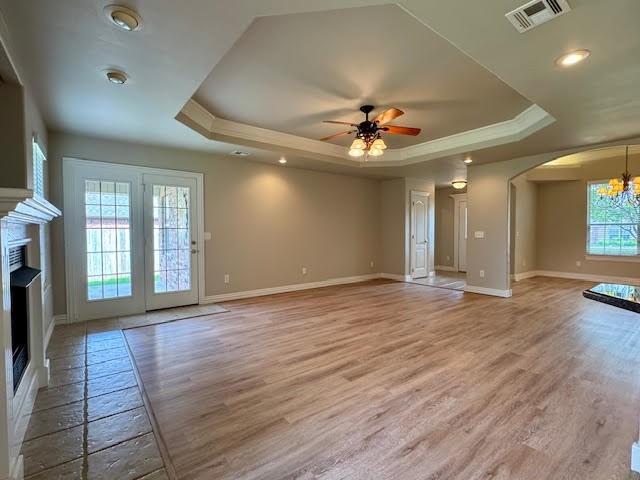 108 Hoss St, Centerton, AR 72719 - unfurnished living room with a raised ceiling, baseboards, a chandelier, arched walkways, and ornamental molding