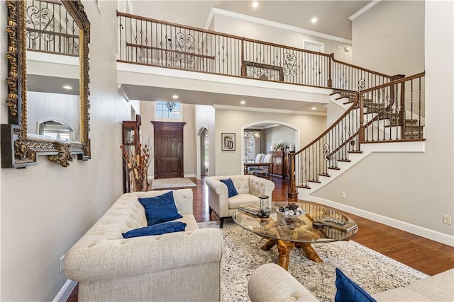5304 S Promontory Ct, Rogers, AR 72758 - living room with arched walkways, wood finished floors, stairs, a high ceiling, and ornamental molding