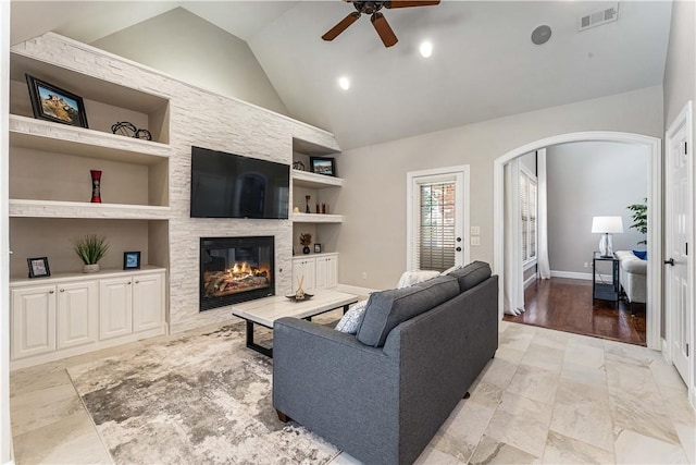 5304 S Promontory Ct, Rogers, AR 72758 - living room featuring built in shelves, arched walkways, a large fireplace, ceiling fan, and high vaulted ceiling