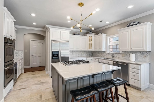 5304 S Promontory Ct, Rogers, AR 72758 - kitchen with stainless steel appliances, ornamental molding, a kitchen bar, white cabinets, and arched walkways