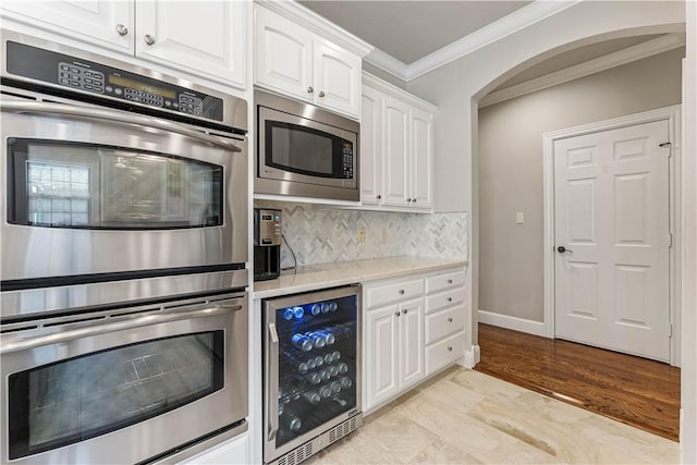 5304 S Promontory Ct, Rogers, AR 72758 - kitchen featuring beverage cooler, appliances with stainless steel finishes, crown molding, white cabinetry, and light countertops