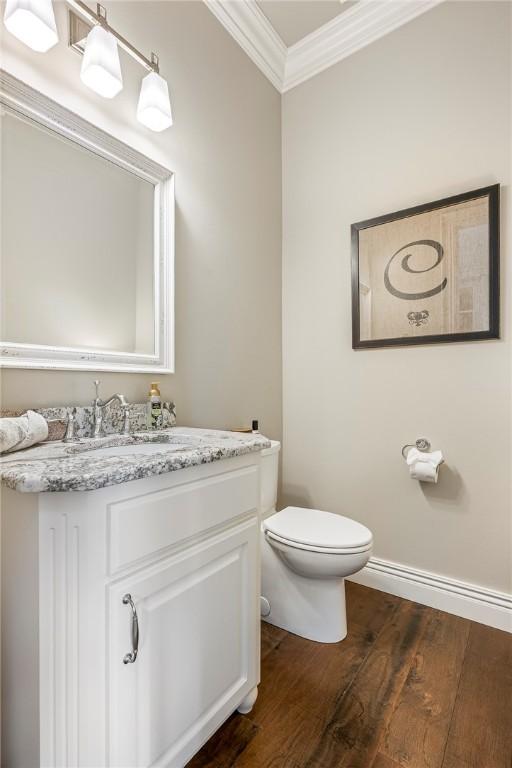 5500 SW Gunstock Rd, Bentonville, AR 72713 - half bathroom with ornamental molding, vanity, toilet, wood finished floors, and baseboards