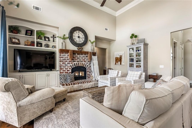 5500 SW Gunstock Rd, Bentonville, AR 72713 - living room featuring a ceiling fan, ornamental molding, a fireplace, built in features, and a towering ceiling