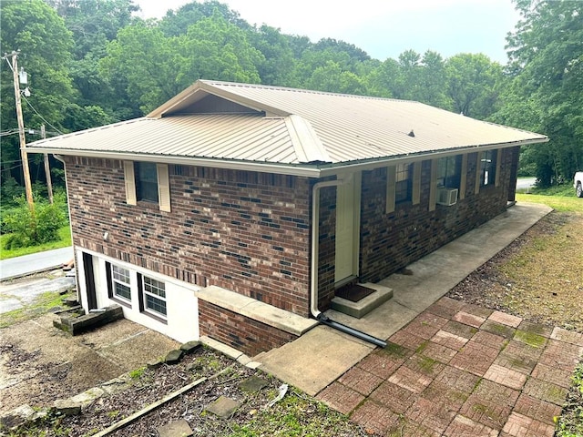 321 F Hwy, Anderson, MO 64831 - view of property exterior with metal roof, brick siding, entry steps, and a view of trees