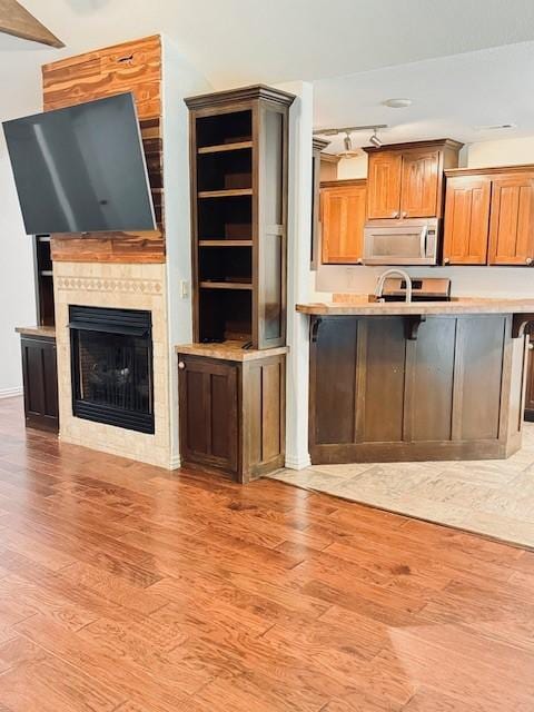 1117 Nemett Dr, Pea Ridge, AR 72751 - kitchen with light wood-style floors, a fireplace, light countertops, brown cabinets, and a breakfast bar