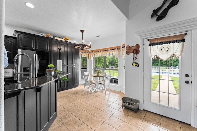 12976 Hummingbird Rd, Elkins, AR 72727 - kitchen with stainless steel fridge with ice dispenser, a chandelier, light tile patterned flooring, dark stone counters, and a textured ceiling