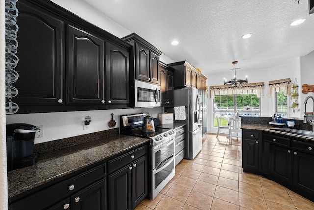 12976 Hummingbird Rd, Elkins, AR 72727 - kitchen with stainless steel appliances, a sink, dark cabinets, a chandelier, and light tile patterned flooring